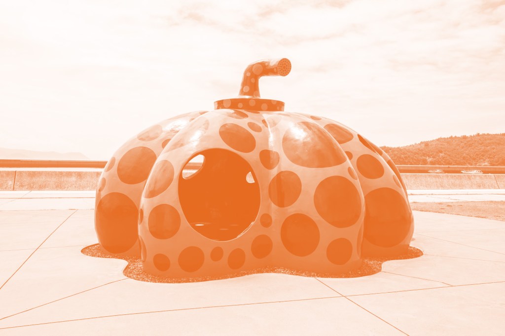 An orange-tinted image of a large pumpkin-shaped sculpture.